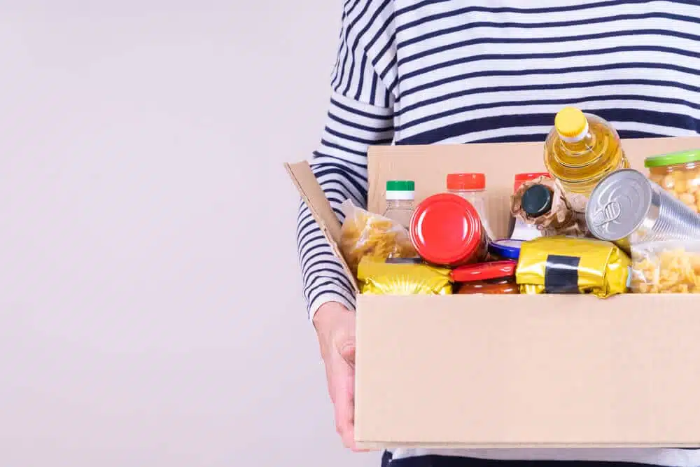 person holding box of canned food